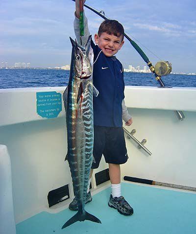 Young angler holding up a wahoo aboard Spellbound, Miami