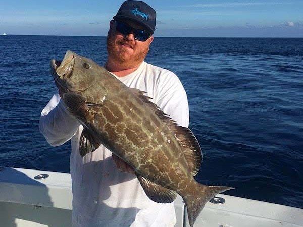 Angler with a black grouper on a half day charter aboard Spellbound, Miami